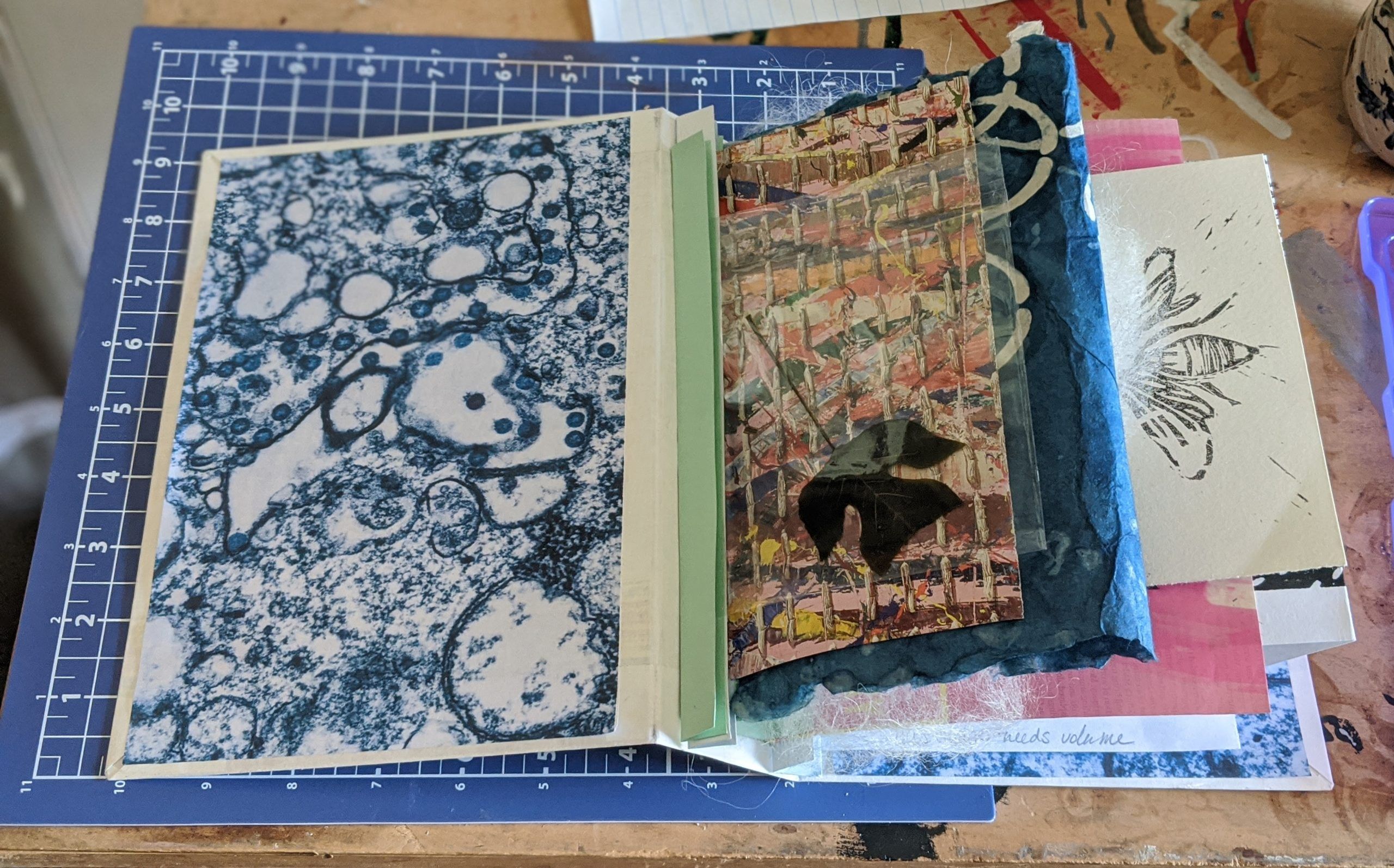 Image is of the front cover of a red and purple accordion book, tied with purple ribbon.