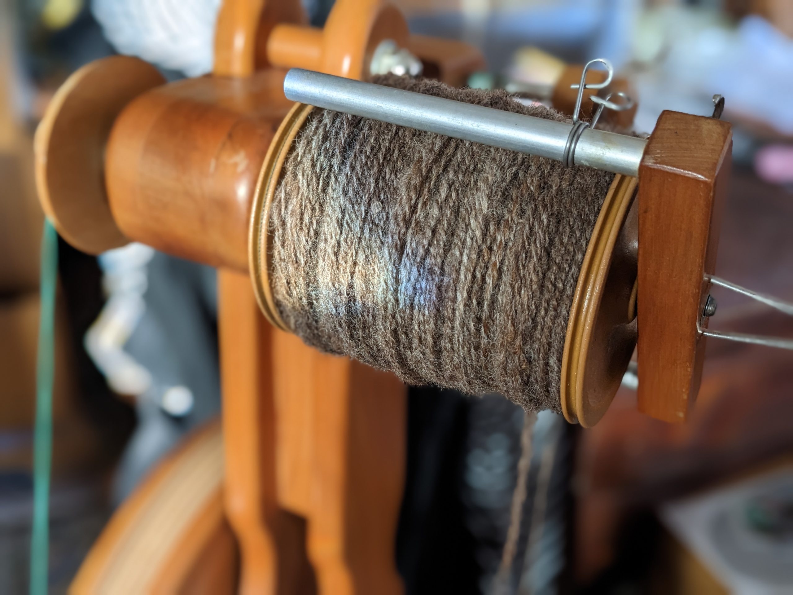 A bobbin full of handspun yarn, plied. The yarn is gray-brown and woolen.